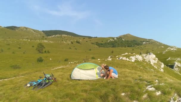 DRONE: Pareja activa preparando su camping durante la aventura ciclista de montaña . — Vídeo de stock