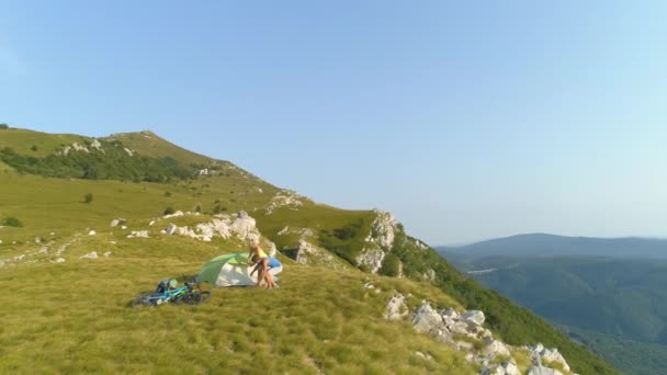 AERIAL: Mann und Freundin bereiten ein Zelt vor, um den Tag in den Bergen zu verbringen. — Stockvideo