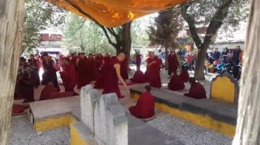 Ziyaretçiler, Lhasa 'daki keşişleri felsefe sınavı için tartışıp pratik yaparken izliyor.