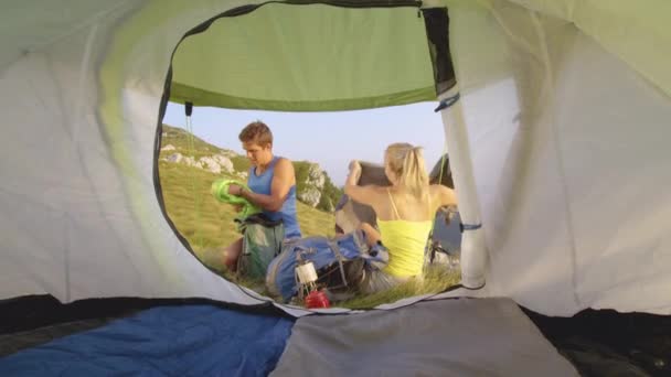 ZAMKNIJ: Turyści pakujący plecaki przed namiotem przed powrotem do domu. — Wideo stockowe