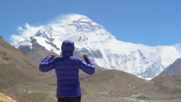 Sluiten omhoog: klimmer reikt overwinnend zijn armen uit terwijl hij de Mount Everest observeert. — Stockvideo