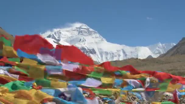 CLOSE UP: Wild wind sweeps snow off mountaintop and makes colorful flags flutter — Stock Video