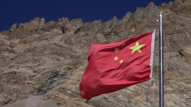 CLOSE UP: Chinese vlag golven onder de rotsachtige bergketen in het zonnige Himalaya. — Stockvideo