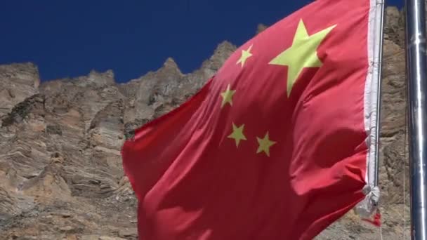 ZAMKNIJ SIĘ, DOF: Chińska flaga fale pod skalistym pasmem górskim i czyste błękitne niebo. — Wideo stockowe