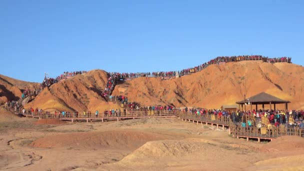 Masses of tourists move along the walkways leading up a hill in Danxia mountains — Stock Video