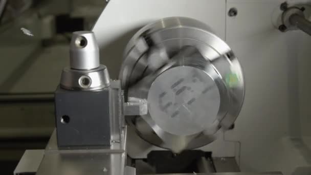 CLOSE UP: Small piece of aluminium is spun by a CNC machine to shave its edges — Stock Video