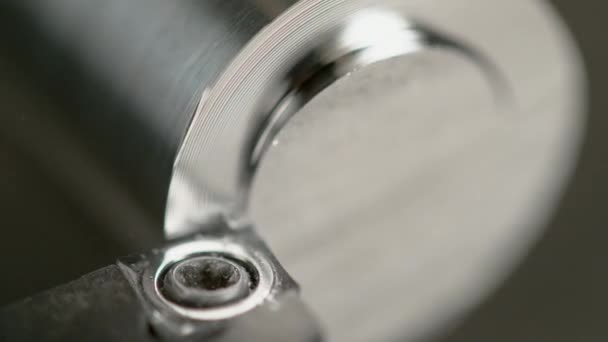 MACRO: Kleine spiralen van metaal vliegen van een metalen cilinder die door een draaibank wordt verwerkt. — Stockvideo
