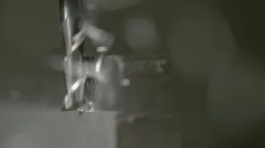 Metal bir bloğun kenarını traş ederken ince uçlu değirmenin detaylı görüntüsü..