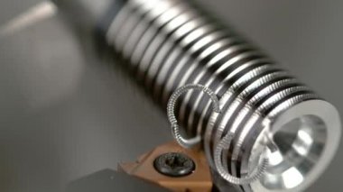 CNC makinesi yavaş yavaş küçük metal bir parçayı parlak bir vidaya sokuyor.