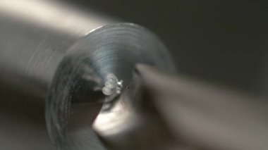 Keskin matkap, parlak metal bir çubuğun ortasında delik açıyor..