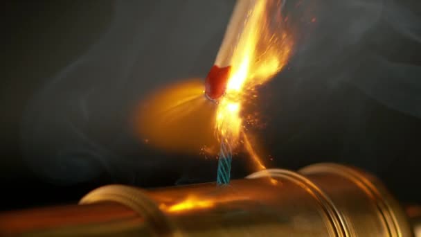 MACRO: Палаючий матч запалює короткий синій запобіжник мініатюрної латунної гармати . — стокове відео