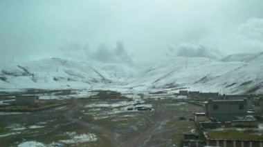 Tibet 'te küçük bir kırsal kasabanın arkasındaki pürüzsüz kar manzaralı tepeler