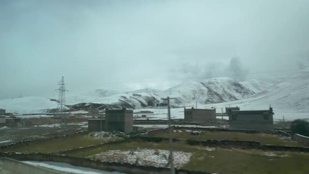 Gite in treno oltre un piccolo villaggio sotto le colline innevate nel suggestivo Tibet . — Video Stock