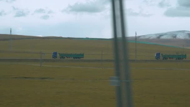 İki büyük yük kamyonu Tibet ovalarından kırsal yolda hızla geçiyor.. — Stok video