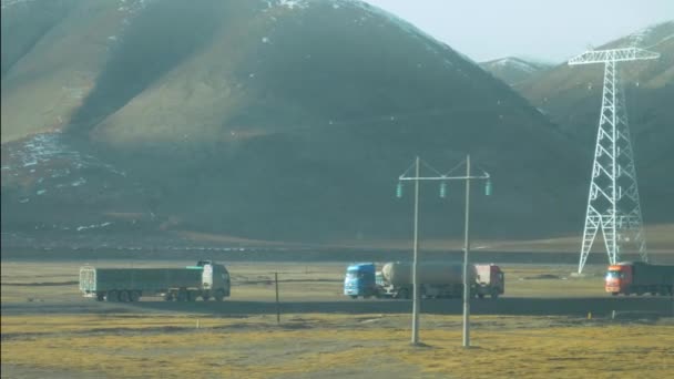 SLOW MOTION: Duże ciężarówki spotykają się przewożąc ładunek po równinach tybetańskich. — Wideo stockowe