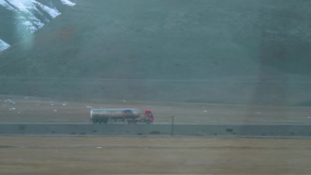 Camion che trasporta una cisterna guida lungo una strada vuota che attraversa le pianure tibetane — Video Stock