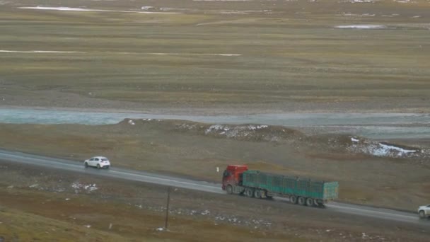 Vrachtwagen haalt auto 's in als hij langs een mooie diepblauwe rivier rijdt. — Stockvideo