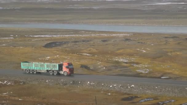 Старий вантажний автомобіль рухається по безлюдній дорозі, перетинаючи мальовничі тибетські рівнини.. — стокове відео