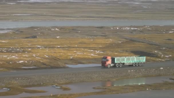 Старий вантажний автомобіль рухається по безлюдній дорозі через мальовничі тибетські рівнини.. — стокове відео