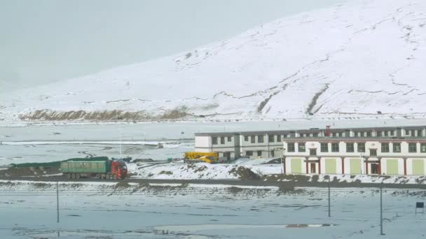 SLOW MOTION: Vrachtwagen vervoert vracht langs een klein landelijk stadje in Tibet. — Stockvideo