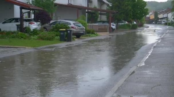 SLOW MOTION: L'acqua piovana copre la strada che passa davanti alle case a schiera in periferia — Video Stock