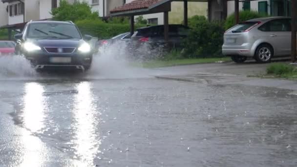 CLOSE UP SUV spat vuil regenwater op camera als het rijdt door de buitenwijken — Stockvideo