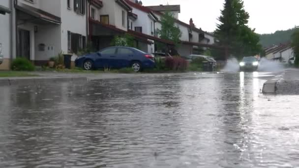 LOW ANGLE Blauer SUV fährt durch die überfluteten Straßen eines Vorortviertels — Stockvideo