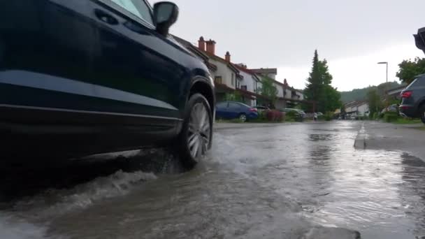 LOW ANGLE: SUV przejeżdżający przez zalane przedmieścia w deszczowy wiosenny dzień. — Wideo stockowe