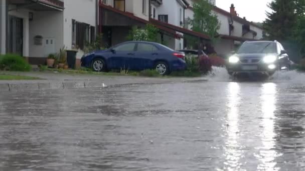 NOWOŚĆ Kąt: SUV chlapie wodą deszczową przed kamerą jadąc przez przedmieścia — Wideo stockowe