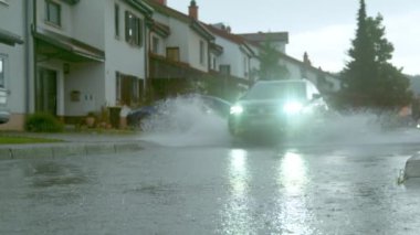 Su basmış caddede parlak farları olan mavi bir SUV sürüyordu..