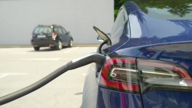 Boş bir otoparkta yüksek teknolojili metalik mavi araba ücreti..
