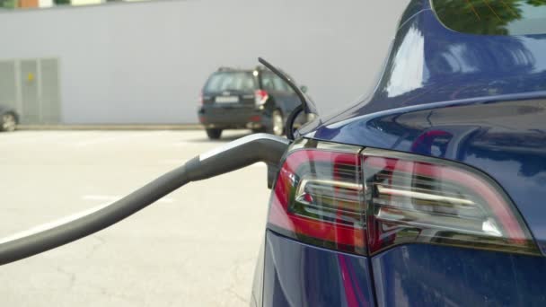 가까이 서 사진: 주차장에서 충전하고 있는 반짝 이는 새 테슬라 자동차의 세부 사진. — 비디오