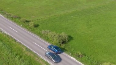 Mavi Tesla 'lı turist kırsal kesimden manzaralı yoldan geçiyor.