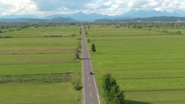 DRONE: Latanie za autonomicznym samochodem jadącym prostą drogą wiejską. — Wideo stockowe