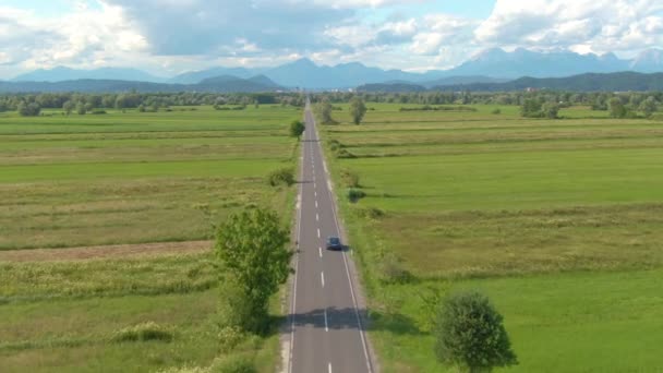 AERIAL: Veículo autônomo azul escuro desce pela estrada rural reta. — Vídeo de Stock