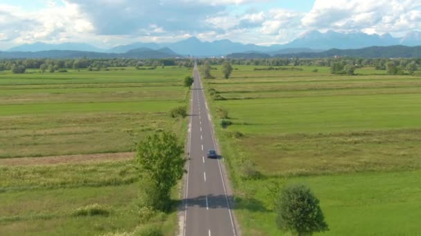 AERIAL: Dark blue autonomous vehicle drives down the straight country road. — Stock Video