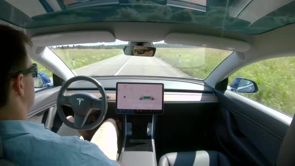 Junger Mann lässt sich vom selbstfahrenden Auto durch die Landschaft chauffieren. — Stockvideo