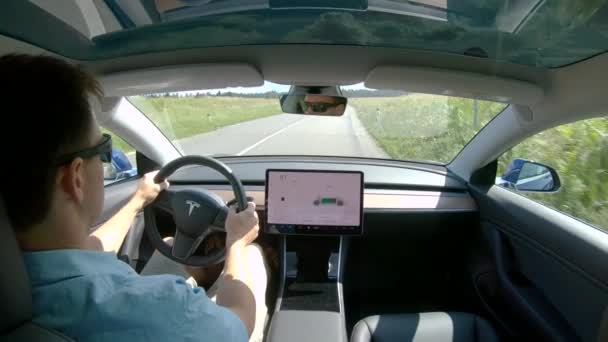 FECHAR UP: Jovem dirige pela estrada rural vazia em um Tesla de alta tecnologia . — Vídeo de Stock