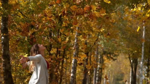 ESPACIO DE COPIA: La mujer extiende sus brazos mientras hojas coloridas vuelan desde los toldos — Vídeo de stock