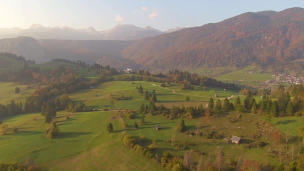 AERIAL Scenic tiro da cidade rural sob as montanhas coloridas e pastos verdes — Vídeo de Stock