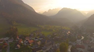 Gün batımında renkli ormanlarla çevrili manzaralı bir kasabanın üzerinde uçmak..