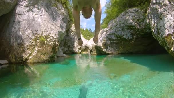 CLOSE UP: Mannelijke reiziger die Slovenië verkent duikt eerst in de Soca rivier. — Stockvideo