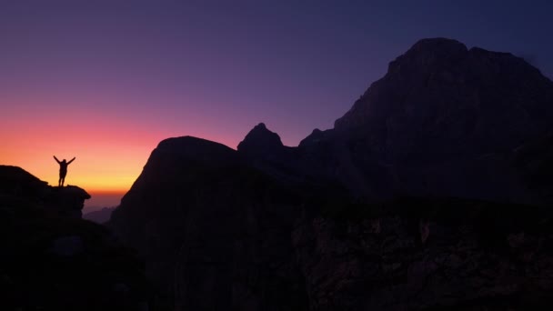 SILHOUETTE: Cinematic shot of a hiker outstretching arms after reaching summit — Stock Video