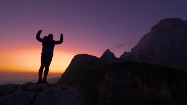 L'escursionista alza le braccia vittoriosamente dopo aver raggiunto la cima all'alba . — Video Stock