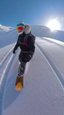 Kayalıklardaki yeni Jones snowboard 'unda snowboard yapan kadın turist..