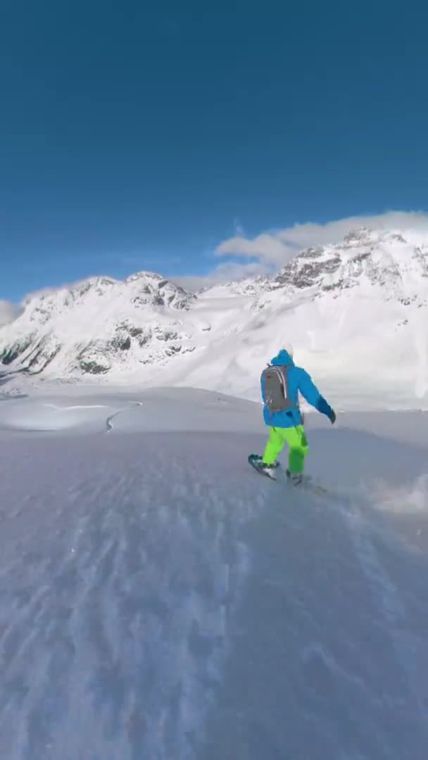 VERTICAL: Rijden op een snowboard achter een pro rider versnipperen van het verse poeder. — Stockvideo