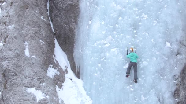 DRONE, COPY SPACE: Neohrožená žena vyleze na nádherný zamrzlý vodopád. — Stock video