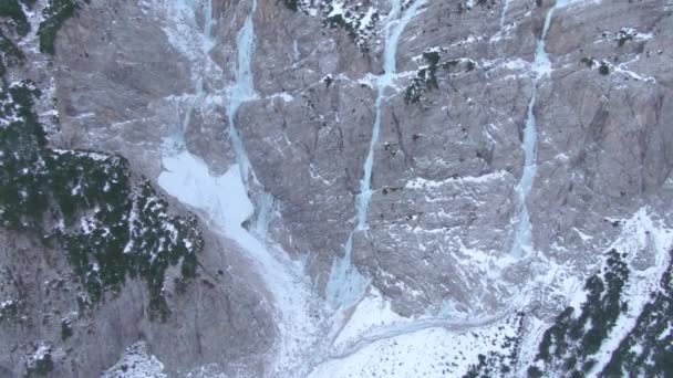 AERIAL: Létání v blízkosti skalnatého útesu a zamrzlých vodopádů ve slovinských horách — Stock video