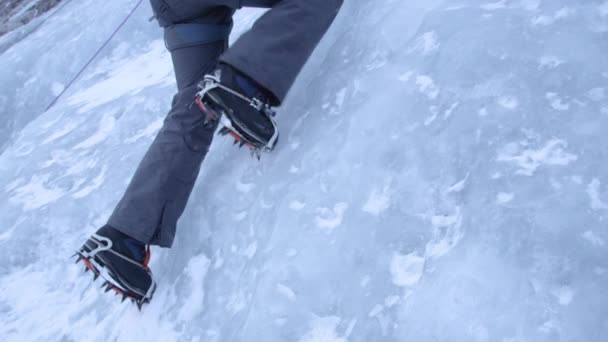 CERRAR UP Alpinista clava sus crampones en el hielo mientras sube por el arroyo congelado — Vídeos de Stock