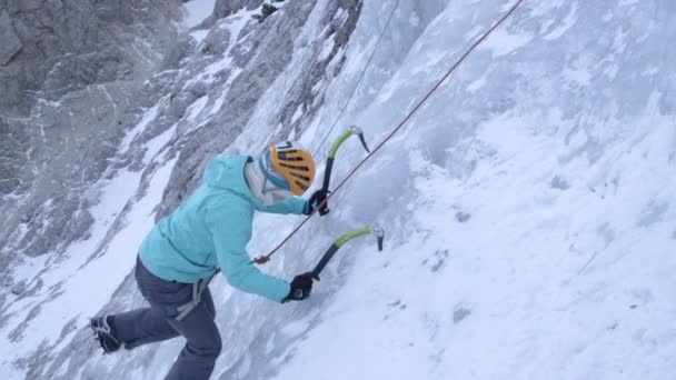 CLOSE UP Mujer colocando cuidadosamente sus hachas de hielo mientras sube por una cascada helada — Vídeos de Stock